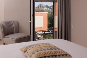 a bedroom with a bed and a chair and a window at Corfu Town Luxury Studio -C in Corfu Town