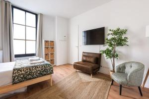1 dormitorio con 1 cama, 1 silla y TV en Bordeaux Districts, en Le Bouscat