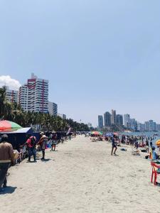 a group of people on a beach with umbrellas at Suite Hermosa ven descansa o trabaja El Rodadero Santa Marta in Gaira