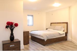 a bedroom with a bed and a vase with red flowers at Luxury en-suite rooms in Southampton