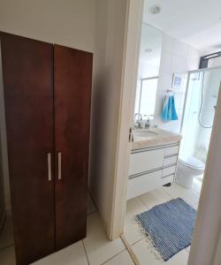 a bathroom with a brown cabinet and a sink at Apartamento Aconchegante in Ribeirão Preto