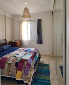 a bedroom with a bed with a colorful quilt on it at Apartamento Aconchegante in Ribeirão Preto