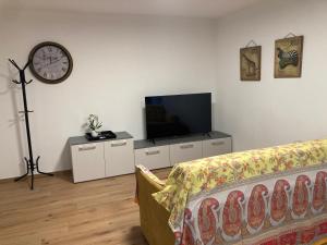 a living room with a couch and a tv and a clock at Casa Teresa in Germignaga