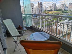 a balcony with a table and chairs and a view of a city at Apartamento Aconchegante in Ribeirão Preto