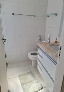 a white bathroom with a toilet and a sink at Apartamento Aconchegante in Ribeirão Preto