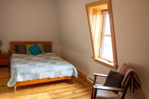 1 dormitorio con cama, ventana y silla en La Vérivraie/Truly -Hébergement touristique/Tourist accomodation, en North Hatley
