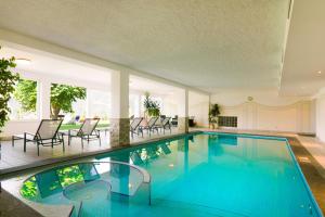 a swimming pool with blue water in a house at Hotel Schönbrunn in Schenna