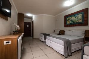 a hotel room with two beds and a television at Havana Express Uberaba in Uberaba +20 photos