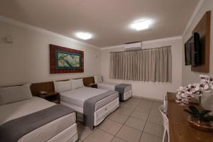 a hotel room with two beds and a tv at Havana Express Uberaba in Uberaba