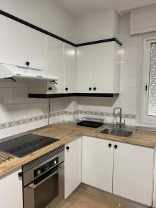 una cocina con armarios blancos y fregadero en Apartamento El Nogal 2, en Tui