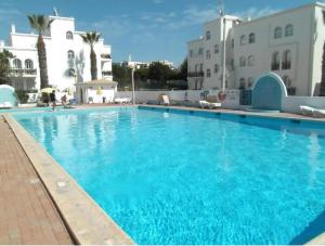 a large blue swimming pool with buildings in the background at Tavira Garden Oasis in Tavira