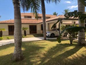 une voiture garée devant une maison avec des palmiers dans l'établissement VILLA GUAVABERRY n, à Paraíso