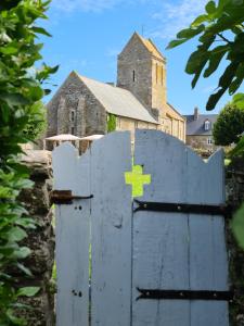 a gate with a yellow arrow on it in front of a church at Prieuré saint Léonard, XIème siècle, Baie du mont saint Michel in Vains