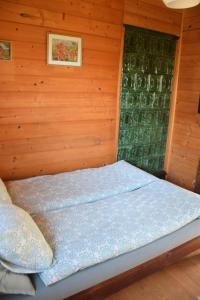 a bed in a room with a wooden wall at Málnás Vendégház-Raspberry Guesthouse in Nagymaros
