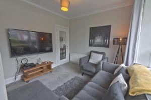 uma sala de estar com um sofá e uma televisão de ecrã plano em Modern home w private driveway and garden near Belfast City Centre em Belfast