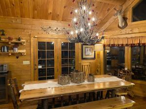 a dining room with a wooden table and a chandelier at Beautiful 6 bdr cabin with hot tub in the Smokies! in Pigeon Forge