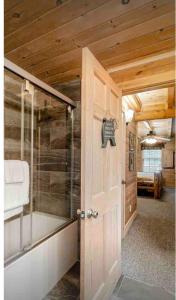 a bathroom with a shower and a door with a tub at Beautiful 6 bdr cabin with hot tub in the Smokies! in Pigeon Forge