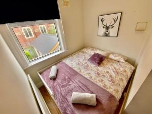 um pequeno quarto com uma cama e uma janela em Modern home w private driveway and garden near Belfast City Centre em Belfast