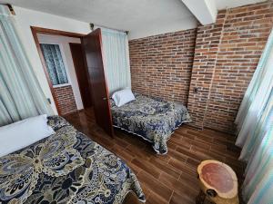 a room with two beds and a brick wall at Cabañas Morales in Zacatlán