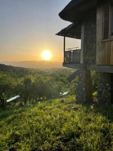 a sun setting behind a house with a balcony at Adere Safari lodge 