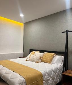 een slaapkamer met een bed met witte lakens en gouden kussens bij Matamoros 11 in Tepoztlán