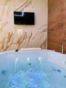 a bath tub with a television on a wall at Suite169 Gold in Bari