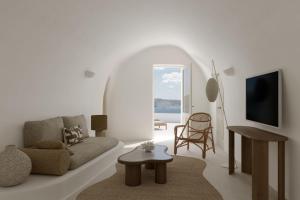 a white living room with a couch and a table at Mystique, a Luxury Collection Hotel, Santorini in Oia