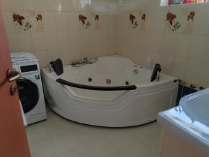 a white bath tub in a bathroom next to a washing machine at NORA Guesthouse and Restaurant in Zamárdi