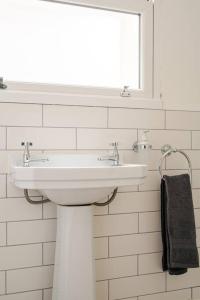 The Snug Den في Kent: حمام أبيض مع حوض ومرآة
