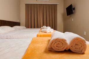 a hotel room with two beds with towels at Vila Castelo Residencial no Centro de Foz in Foz do Iguaçu