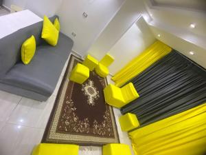 uma sala de estar com cadeiras amarelas e um sofá em Pyramids Apartment no Cairo