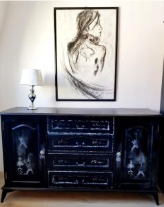 a black dresser with a drawing on the wall at Gold Apartament in Wałbrzych