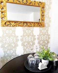 a table with glasses and a mirror on a wall at Gold Apartament in Wałbrzych