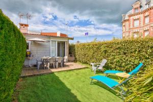 a backyard with chairs and tables and a hedge at La Casa Vega - Casino, plage et parking in Villers-sur-Mer