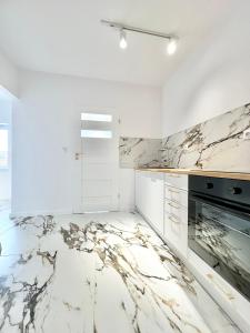 a white kitchen with marble counter tops at Apartament Opolska 5 in Tarnowskie Góry