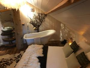 a bathroom with a bath tub and a couch and a couch at Les Cabanes de Koad'dour - séjour SPA dans les arbres in Les Portes du Coglais