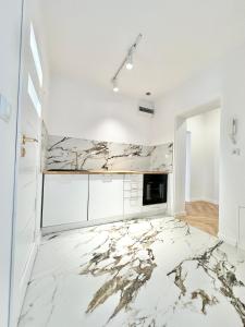 a white kitchen with marble flooring and white cabinets at Apartament Opolska 5 in Tarnowskie Góry