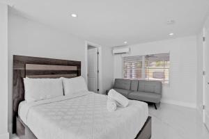 een witte slaapkamer met een groot bed en een bank bij Pompano Gem, 1 mi to Beach & 12 Pickleball courts in Pompano Beach