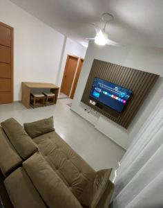 Apartamento vista mar 72 في برايا جراندي: غرفة معيشة مع أريكة وتلفزيون بشاشة مسطحة