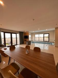 un soggiorno con un grande tavolo in legno e una piscina di Continent Hotel Al Uqayr فندق كونتننت العقير 