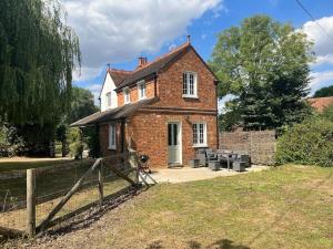 a brick house with a fence in front of it at The Cottage, Marlow in Buckinghamshire