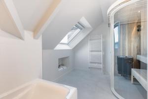 a white bathroom with a tub and a window at Hôtel Spa De La Citadelle Lorient in Port-Louis