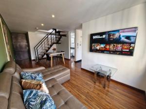Una sala de estar con un sofá y un televisor en la pared. en Suites and Apartments Bogotá, en Bogotá
