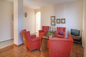a living room with red chairs and a television at Vista Alegre in Benicàssim