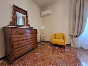 een slaapkamer met een dressoir met een spiegel en een gele stoel bij La Corticella in Lucca