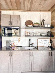 cocina con armarios blancos y encimera en Modern Tiny Home, 