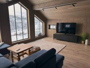 a living room with a couch and a tv at Høgerinden Lodge in Sogndal