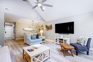 a living room with a couch and a tv at The Palm Frond Stay in Isle of Palms