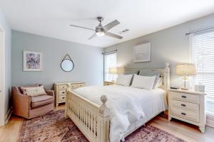 a bedroom with a white bed and a chair at The Palm Frond Stay in Isle of Palms