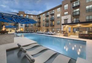 a large swimming pool with chairs and a building at Luxury Condo-Style Hotel In Domain Shopping Center in Austin